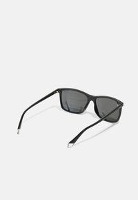 Black sunglasses with a rectangular shape, glossy plastic frame, dark lenses, and thin, tapered arms featuring silver accents.