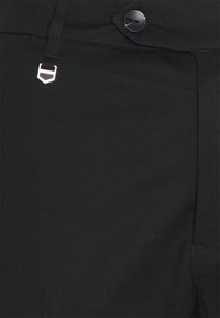 Svarta byxor i ett slätt tyg, med knappstängning, ett litet märke nära midjan och rak skärning.