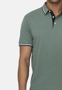 Polo shirt in gedempt groen katoen met een zwarte kraag en witte streepaccenten, voorzien van een placket met twee knopen en korte mouwen.