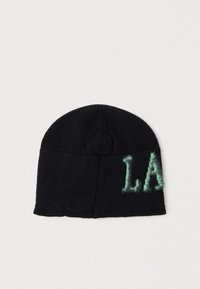 Musta neulottu pipo pyöreällä päällä. Sivulla vaaleanvihreä, pörröinen "L.A."-kirjailu. Pehmeä rakenne, rento muotoilu.