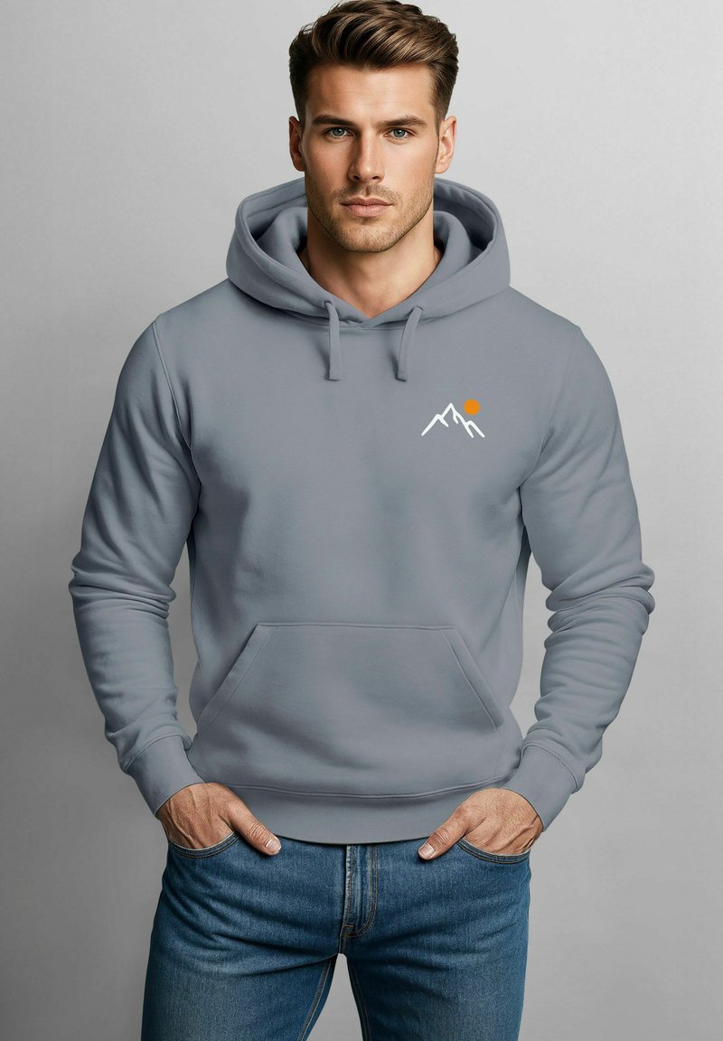 Grauer Hoodie mit einer Fronttasche, der weiße Berggrafiken und eine orangefarbene Sonne zeigt. Hergestellt aus weichem Stoff, mit gerippten Bündchen und Saum.