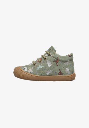 Zapatillas de cuero ante verde para niños con suela de goma marrón y cordones, decoradas con estampados de dinosaurios coloridos.