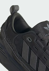 Μαύρο αθλητικό παπούτσι με συνδυασμό υφασμένου σουέτ και λείο δέρμα, με επενδεδυμένο κολάρο και χαρακτηριστικό σχέδιο ρίγας.