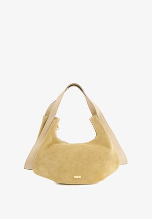 Suede beige handbag with a smooth leather strap. Curved silhouette, large opening. Gold-tone hardware detail on the front. Soft texture.