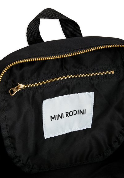 Interior de mochila em tecido preto com um bolso de fecho éclair e uma etiqueta branca com "MINI RODINI" em texto preto. Ferragens douradas do fecho éclair visíveis.