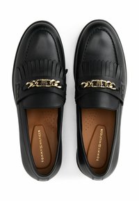 Mocassini in pelle nera con dettagli in frange e accenti in catena dorata, marchiati Tommy Hilfiger su solette color crema.