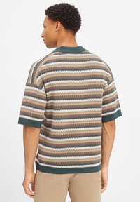 Gestreepte gebreide polo in bruin, crème en groen. Heeft korte mouwen, ribgebreide manchetten en een kraag. Textuurpatroon overal.