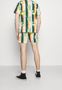 Korte mouwen shirt en korte broek set, met een gedurfd patroon van citroenen en strepen in groen, oranje en geel. Gemaakt van katoen, casual pasvorm.