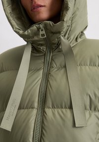 Groene pufferjack met een hoge kap, voorzien van een ritsluiting, brede stoffen banden en een geplooide textuur. Gemaakt van lichtgewicht, glanzend materiaal.