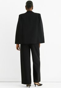 Black suit with a structured blazer and wide-leg trousers. Features a tailored cut, smooth texture, and a minimal design without embellishments.