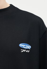 Μαύρο μπλουζάκι με στρογγυλή λαιμόκοψη, με μικρό λογότυπο "barcen MM XVI" σε μπλε και λευκό χρώμα στο αριστερό στήθος.