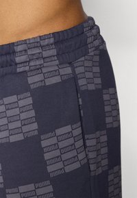 Tamsiai mėlyni sportiniai džinsai, pagaminti iš švelnios medžiagos, su pakartotiniu pilku Puma logotipu. Elastingas juosmuo su matomomis siuvimo detalėmis.