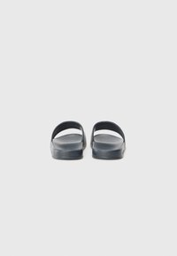 Mørkeblå skyvesandaler med glatt tekstur, åpen bak og brede stropper. Minimalistisk design, flat såle, passende for uformell bruk.