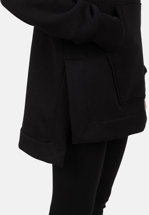 Sweat à capuche noir avec une poche à l'avant, des fentes latérales et une coupe décontractée. Le tissu a une texture lisse, complétée par des détails côtelés.