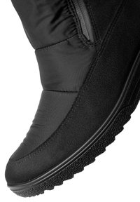 Botín negro impermeable hasta el tobillo con una parte superior de textura suave y una suela de goma con un patrón estriado para mayor tracción. Detalle de cremallera lateral visible.