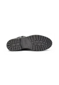 Suela de bota de goma negra con una superficie texturizada, con surcos profundos y patrones cruzados, etiquetada con "FABRICADO EN ESPAÑA" y una marca de tamaño.