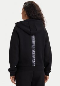 Sudadera con capucha negra hecha de tela suave, con una franja vertical impresa con el logo en la parte posterior y puños y dobladillo acanalados.