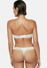 Ensemble de soutien-gorge et thong en dentelle blanche avec un tissu doux, des détails en dentelle délicate et une fermeture à crochets à l'arrière. Les fines bretelles viennent compléter le design.