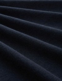 Tissu bleu foncé avec une surface douce et texturée, présentant des plis lisses et fluides qui créent une impression de profondeur et de dimension.