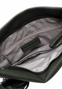 Green leather handbag interior with a smooth, beige fabric lining; features a zippered pocket and an additional slip pocket for organization.