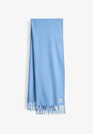 Lichtblauwe sjaal gemaakt van zachte stof. Heeft lange franjes aan één uiteinde en een klein label met een logo in de onderste hoek.