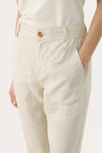Linen trousers in light beige with a loose fit. Features a wide waistband, front pockets, and a single button closure. Smooth texture.