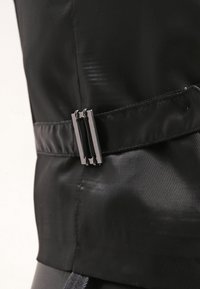 Nahaufnahme eines schwarzen Stoffes mit einem eleganten Design, glatter Textur und einer rechteckigen Metall-Schnalle, die einen Taillengurt akzentuiert.