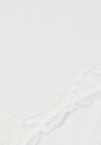 Tessuto di cotone bianco con un delicato e intricato bordo in pizzo lungo un lato. La texture è liscia, mentre il pizzo presenta un motivo a scallop.