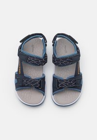 Infradito blu con cinturini regolabili, soletta in gomma grigia con texture, suola in gomma bianca e motivo geometrico sul cinturino superiore.