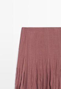 Jupe plissée mauve avec une texture de tissu douce, présentée à plat sur fond blanc.