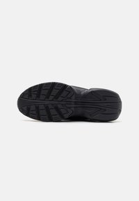 Black athletic shoe sole with a textured rubber tread pattern, featuring a curved design and clearly defined grip lines for traction.