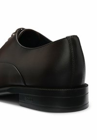 Black leather shoe with a smooth finish, rounded toe, and subtle stitching detail. Features a black rubber sole with embossed logo.