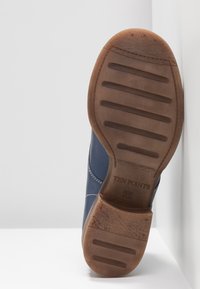 Chaussure en cuir bleu avec une semelle extérieure en caoutchouc. La semelle comporte des rainures horizontales et une marque. Coutures détaillées le long des côtés. Taille 37.