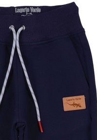 Marineblauwe joggingbroek met een geribbelde tailleband, grijze trekkoorden met rode uiteinden, en een beige label met "Lagarto Verde" en een hagedisontwerp.