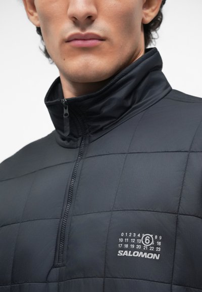 Črna z insulated jakna s četrt-zadrgo, ki ima prešito zasnovo in logo na levem prsnem delu. Gladek, lahek material.