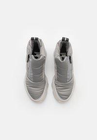 Bottines molletonnées grises avec une tige lisse, une fermeture éclair contrastante et une semelle en caoutchouc texturée. Intérieur noir avec détail de marque.