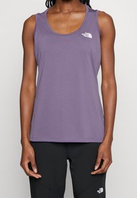 Fioletowy top na ramiączkach wykonany z miękkiego, elastycznego materiału. Posiada okrągły dekolt i małe białe logo na lewej piersi.