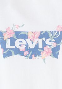Levi's grafiškas T-shirt su mėlyna gėlių kompozicija, kurioje rožinės gėl�ės supa baltą prekės ženklą ant balto fono.