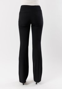 Pantaloni neri a zampa d'elefante con una texture liscia, vita alta e minimi dettagli di cucitura. Ideali per occasioni formali o semi-formali.