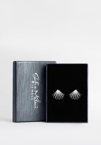 Silverfärgade metallörhängen i en fläktform, visade i en svart sammetsfodrad låda med en strukturerad silverexteriör och logotyp.