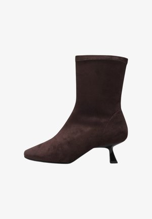 Bottine en daim marron avec un bout pointu et un talon bas évasé. Texture lisse avec une tige ajustée et sans matériel ou accents visibles.