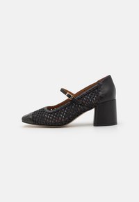 Black leather and woven textile Mary Jane shoes with a chunky heel, featuring a strap and gold buckle. Rounded toe design.