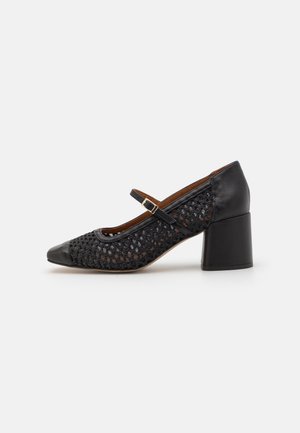 Black leather and woven textile Mary Jane shoes with a chunky heel, featuring a strap and gold buckle. Rounded toe design.