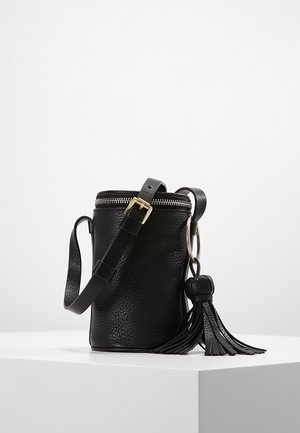Zwarte cilindervormige schoudertas van leer met textuur, verstelbare riem, gouden gesp, ritssluiting en een grote kwastdetail die aan een metalen ring hangt.