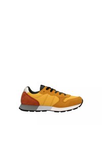 Sneaker gialla con tomaia in suede e mesh, lacci neri, una intersuola bianca e dettagli arancioni sul tallone; suola in gomma piatta.