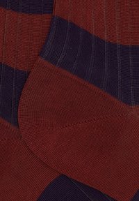 Calze a righe con colori rosso e viola scuro, realizzate in tessuto a costine con cuciture testurizzate. Accenti di righe orizzontali.