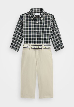 Kostkovaná košeľa s button-up v námořnickej a zelenej farbe, doplnená béžovými nohavicami. Obsahuje opasok so vzorom a prackou, hladká tkanina, strih na mieru.