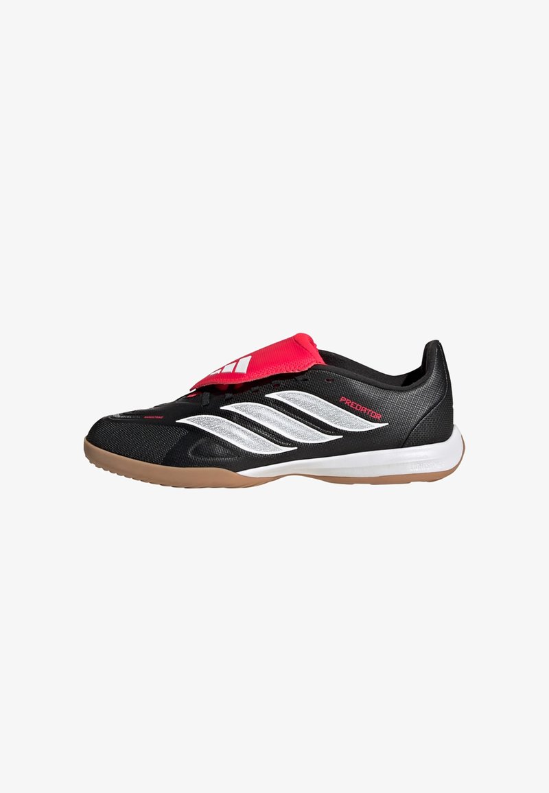 Chaussure de football en salle Adidas Predator basse de couleur noire et rouge avec des rayures blanches et une semelle gomme, vue latérale.