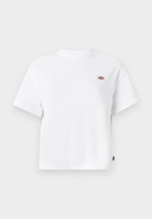 Camiseta blanca de algodón con un corte relajado, que presenta un pequeño parche con logo en el pecho y una etiqueta en el costado para un detalle adicional.
