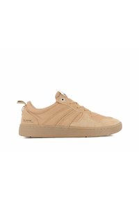 Zapatillas de ante color beige con suela crema texturizada, que presentan un diseño de cordones, rayas laterales y una tira de agarre en el talón. Logo de la marca en el lateral.